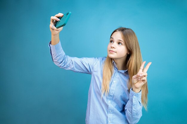 La ragazza si fa una foto su uno smartphone su sfondo blu