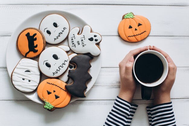 La ragazza si prepara per Halloween, beve il caffè e mangia i pizzicotti di pan di zenzero.