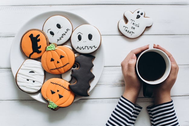 La ragazza si prepara per Halloween, beve il caffè e mangia i pizzicotti di pan di zenzero.