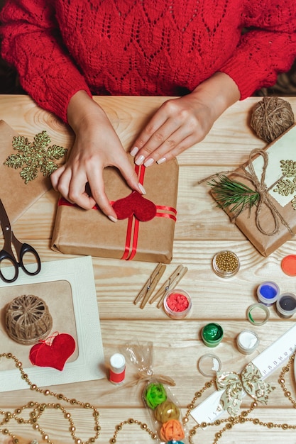 La ragazza si siede al tavolo avvolge i regali di Natale