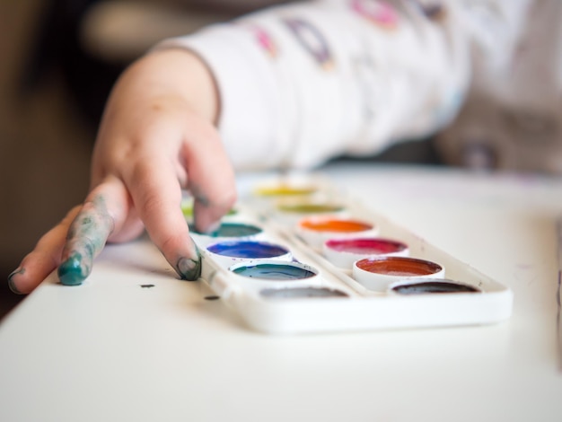 La ragazza si siede al tavolo e disegna con le dita nel quaderno di schizzi Creatività per bambini Hobby per bambini