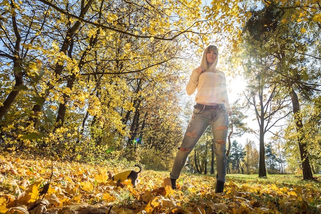 La ragazza si siede e si rilassa per terra nella foresta autunnale