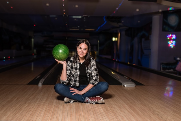 La ragazza si siede e sorride e tiene la palla nel club di bowling