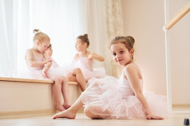 La ragazza si siede sul pavimento Piccole ballerine che si preparano per l'esibizione praticando mosse di danza