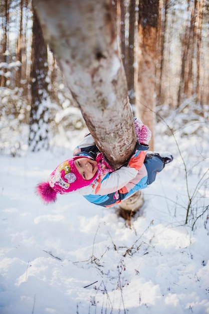 La ragazza si siede sulla neve in tuta nella foresta