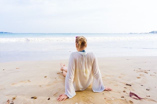 La ragazza si siede sulla riva e guarda il mare