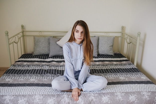 La ragazza si svegliò e si mise in pigiama sul letto nella sua stanza. Elegante interno grigio-bianco.