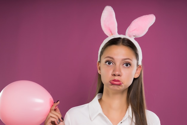 La ragazza si tocca il viso e tiene in mano una palla rosa, isolata