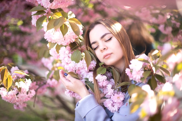 La ragazza si trova sui fiori di sakura. Una bella ragazza dorme in un giardino fiorito