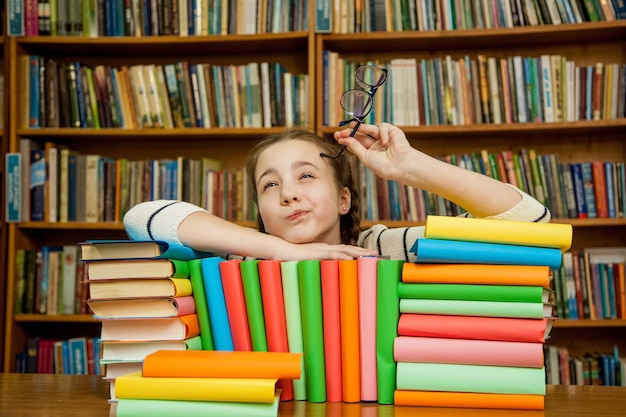 La ragazza sogna con i libri in biblioteca.