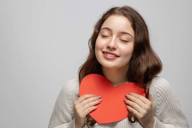 La ragazza sogna e tiene un cuore rosso di cartone, il giorno di San Valentino