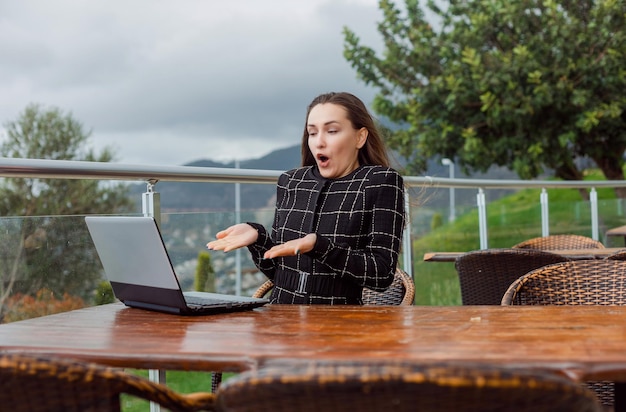 La ragazza sorpresa del blogger sta guardando lo schermo del suo laptop sullo sfondo della vista della natura