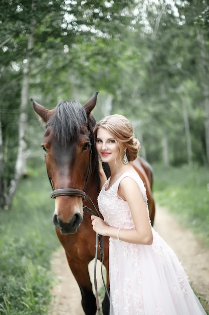 La ragazza sorride abbraccia il cavallo nella foresta