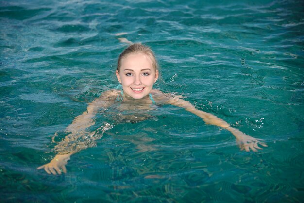 La ragazza sorride mentre nuota in piscina.