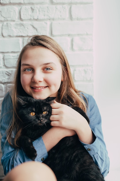 La ragazza sorridente abbraccia un gatto nero