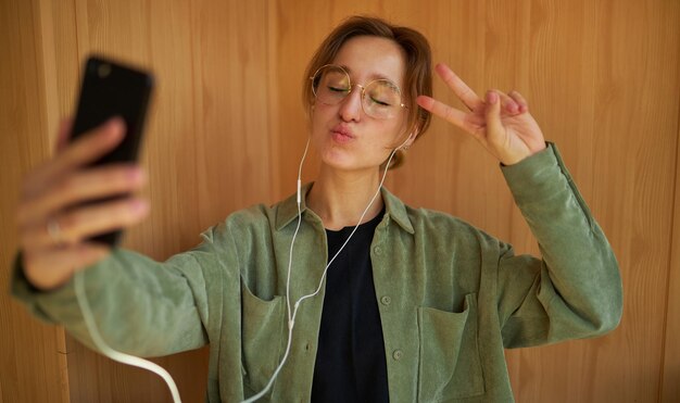 la ragazza sorridente caucasica che utilizza un telefono cellulare comunica con gli amici in una chat video online