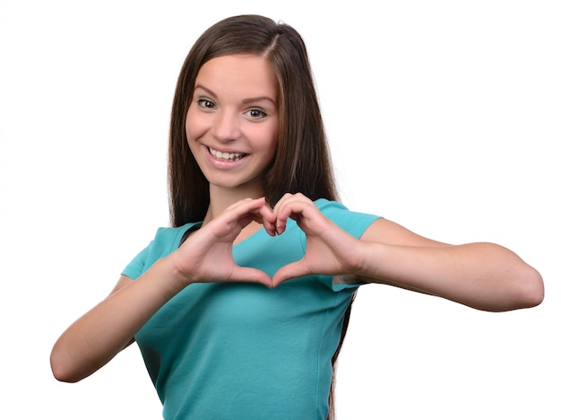 La ragazza sorridente dell&#39;adolescente che fa il cuore modella con le sue mani.