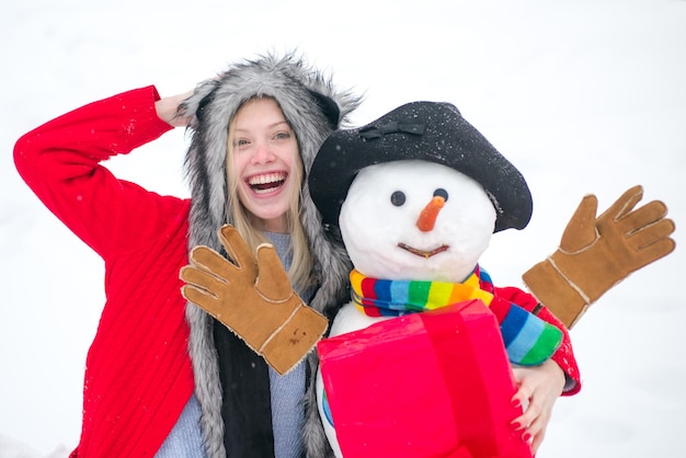 La ragazza sorridente felice fa il pupazzo di neve nella soleggiata giornata invernale clima invernale nel parco inverno ritratto di divertente ...