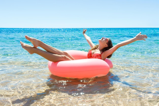 La ragazza sorridente felice gode di galleggiare sulla ciambella gonfiabile in mare. ferie.