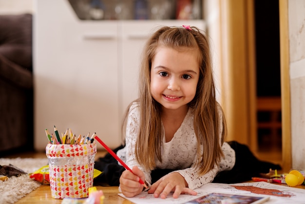 La ragazza sorridente graziosa del bambino sta giocando con le matite colorate.