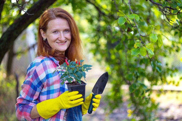 La ragazza sorridente trapianta i fiori nel giardino. vasi da fiori e piante da trapianto