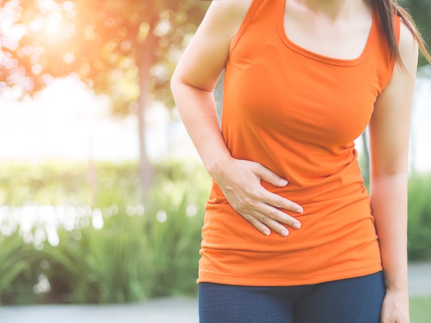 La ragazza sportiva ha mal di stomaco dopo aver fatto jogging nel parco.