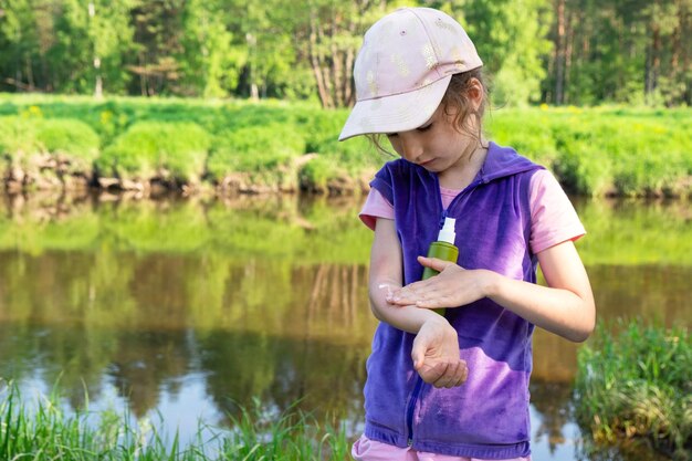 La ragazza spruzza spray antizanzare sulla pelle in natura che le morde mani e piedi Protezione dalle punture di insetti repellente sicuro per i bambini Attività ricreative all'aperto contro le allergie Ora legale