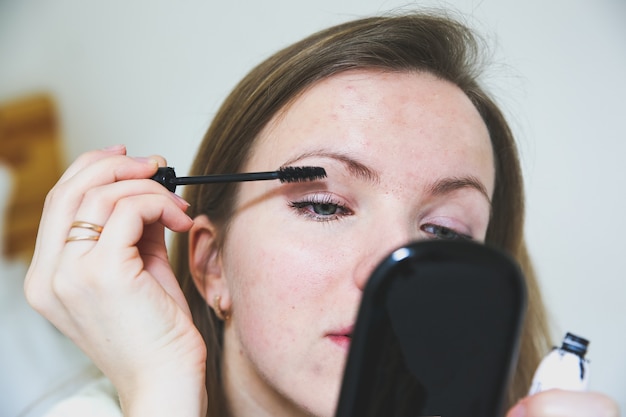 La ragazza sta applicando il trucco. Mascara nero sulle ciglia. Concetto di foto di bellezza.