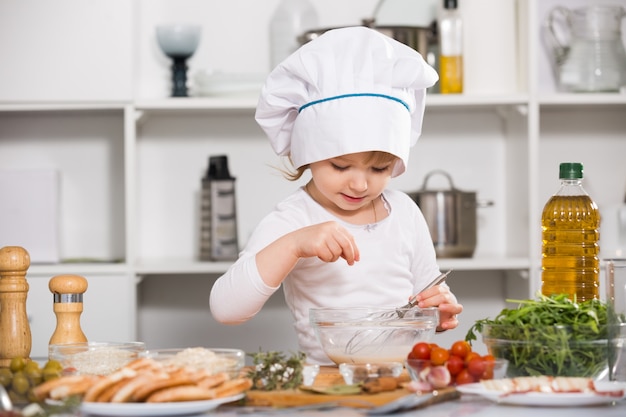 La ragazza sta cucinando la salsa per insalata nella cucina