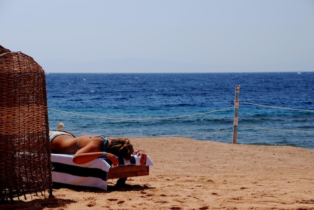 La ragazza sta dormendo sulla spiaggia e sul mare in vacanza