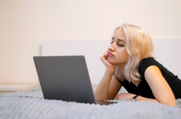 La ragazza sta guardando una serie TV, un film su un laptop. La noia. La fine della serie, il film. La ragazza è sdraiata sul letto.