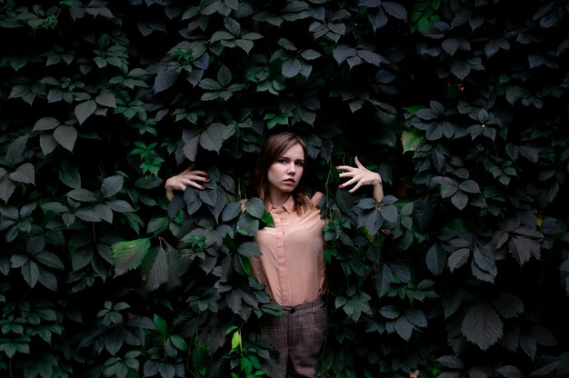 La ragazza sta in foglie verdi da solo con la natura, una donna tocca le piante e i sogni, un concetto di un uomo in natura