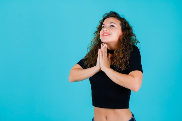 La ragazza sta pregando tenendosi per mano su sfondo blu