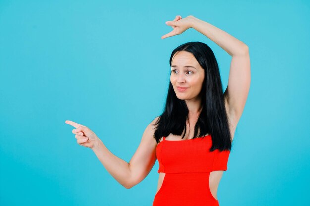 La ragazza sta puntando a sinistra con gli indici su sfondo blu