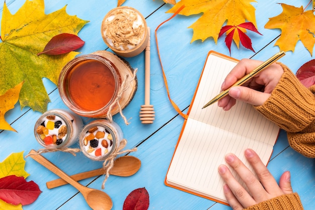 la ragazza sta tenendo un taccuino sulla tavola di autunno.