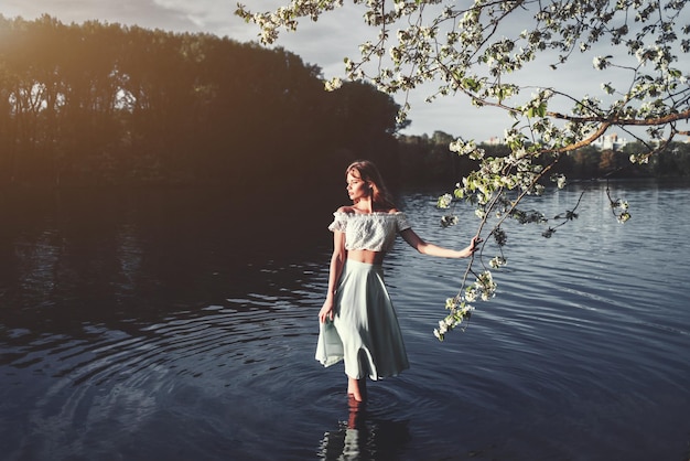 La ragazza sta tra gli alberi in fiore