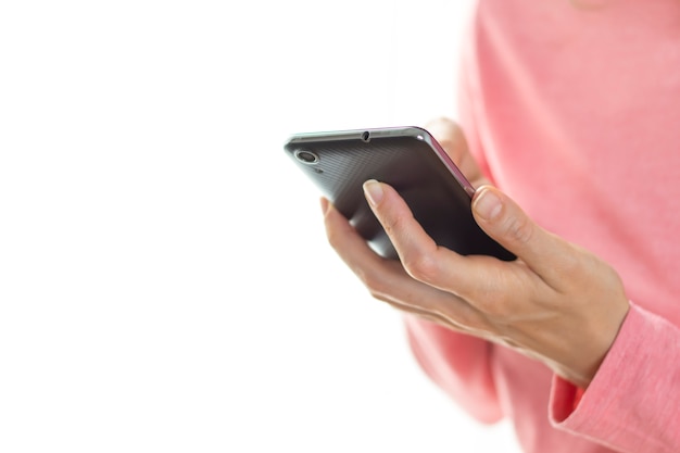 La ragazza sta usando uno smartphone. Primo piano del telefono in mano.