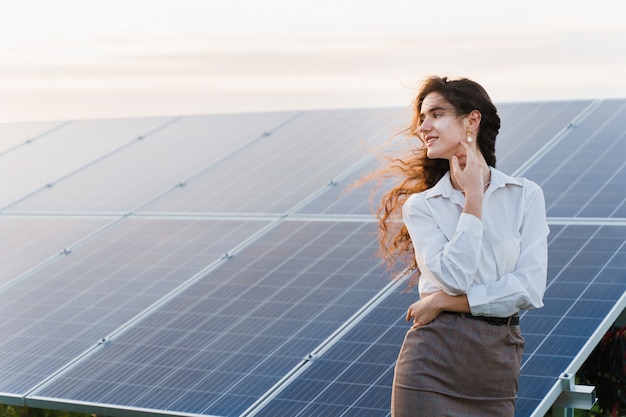 La ragazza sta vicino alle righe del pannello solare sul terreno