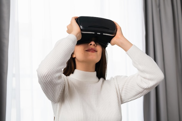 La ragazza stupita nella realtà virtuale che utilizza l'auricolare per occhiali vr esplora il metaverso