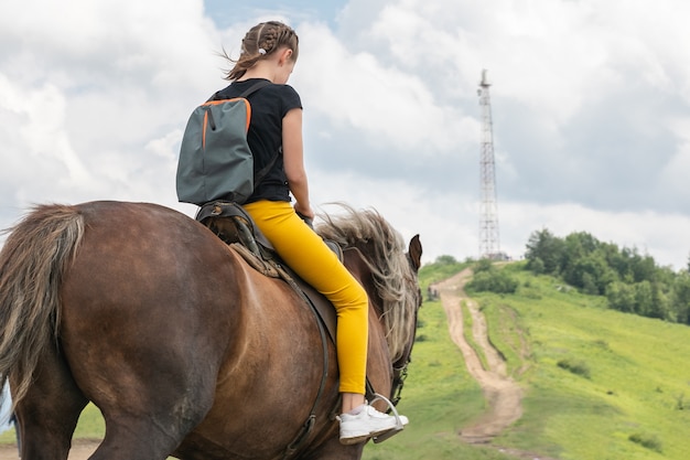 La ragazza su un cavallo mantiene la strada verso la cima dello stile di vita attivo della montagna