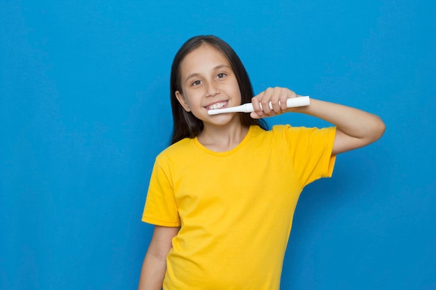 La ragazza su uno sfondo blu si lava i denti