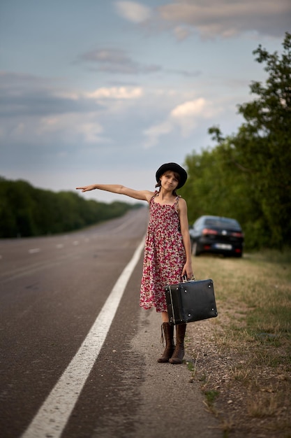 La ragazza sulla strada con la vecchia valigia ha fermato l'auto