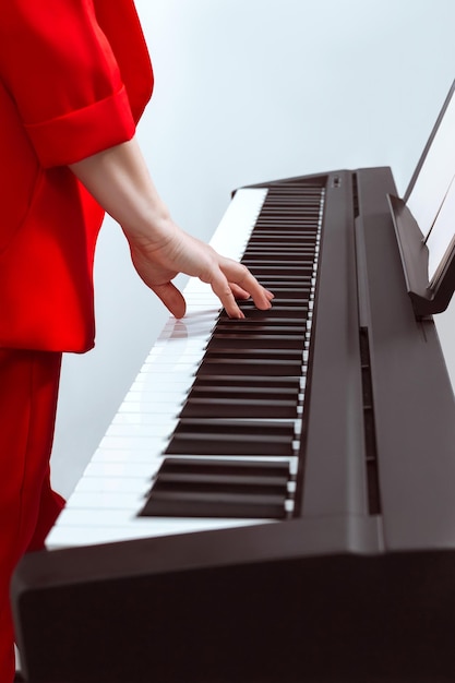 La ragazza suona il pianoforte con una mano Mano del pianista sui tasti primo piano Messa a fuoco parziale