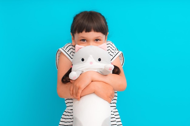 La ragazza sveglia del bambino abbraccia il suo peluche preferito una pagnotta del gatto un giocattolo del cuscino