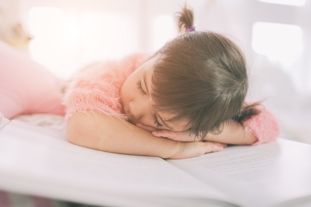 La ragazza sveglia del bambino sta leggendo un libro a casa. Bambino adorabile divertente divertendosi nella stanza dei bambini.