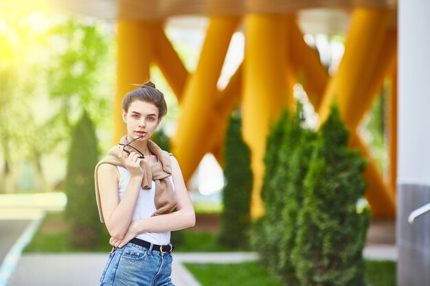 La ragazza sveglia in occhiali da sole cammina attraverso la città.