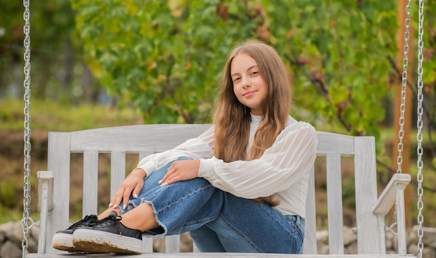 La ragazza teenager all'aperto oscillante del bambino si diverte nel parco giochi la felicità dell'infanzia si rilassa nel parco