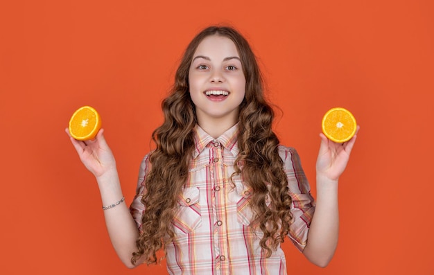 La ragazza teenager felice tiene la frutta agrumata su fondo arancio