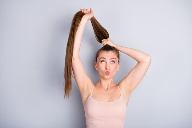 la ragazza tiene i capelli in una coda di cavallo con le mani