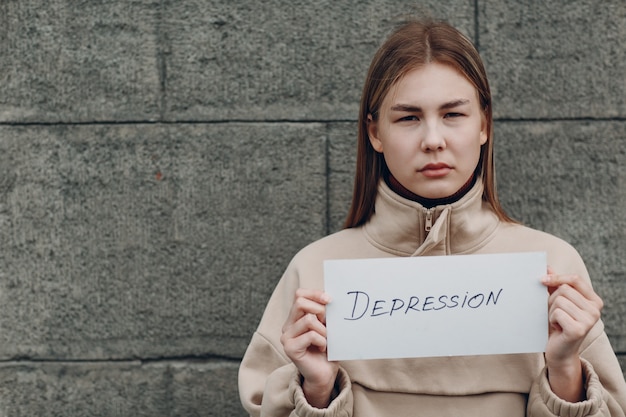 La ragazza tiene in mano il foglio di carta con la parola depressione.